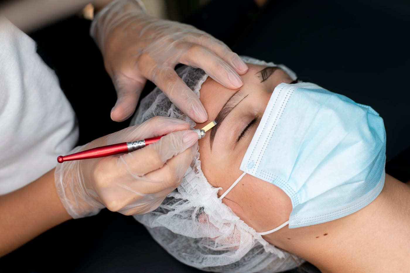 Kosmetička provádí mikropigmentaci obočí v kosmetickém salonu